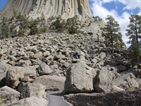 a field of boulders with a paved bath winding through, the base of Devils Tower in the background