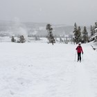 Skier on a trail with a hydrothermal feature steaming in the background