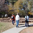 People walk on a path near historical rock squares that used to be structures.