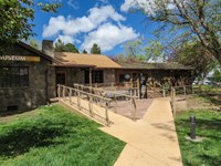 A stone and log house sits at the end of an entry walkway.