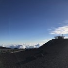 A small building sits in front of a blue sky on top of a rocky hill