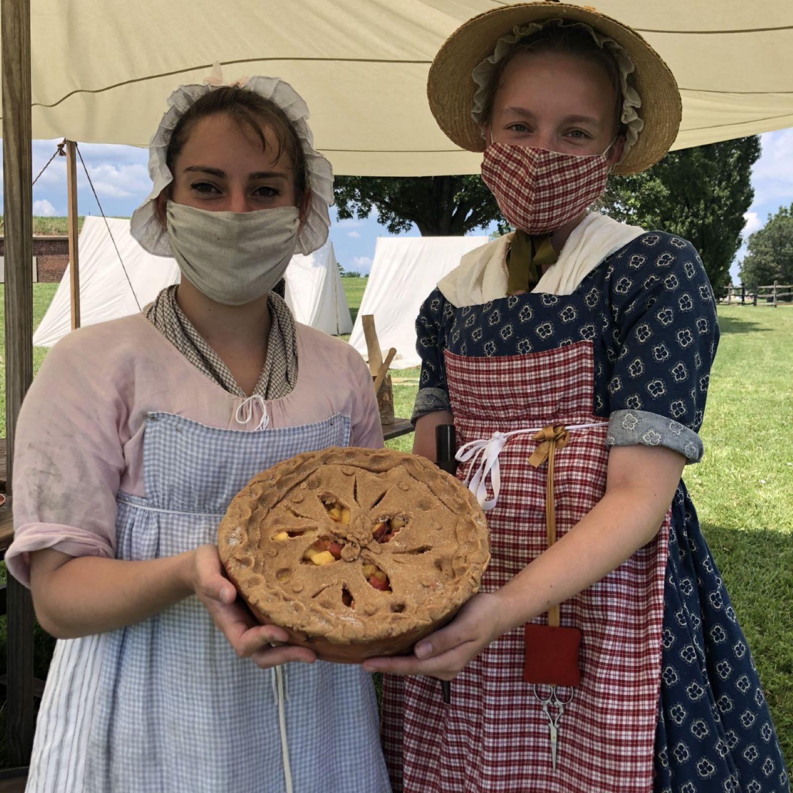 Living historians holding a pie.