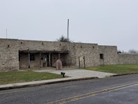 Historic stone structure with a small, covered entrance area and a wall, exhibit, and historical mar