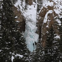 Icicle formations encase a waterfall surrounded by columns of rock.