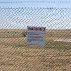 A tall fence with a warning sign that reads 