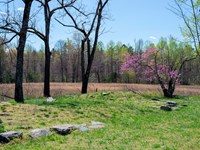 Stone foundations of a house surrounded by an open field.