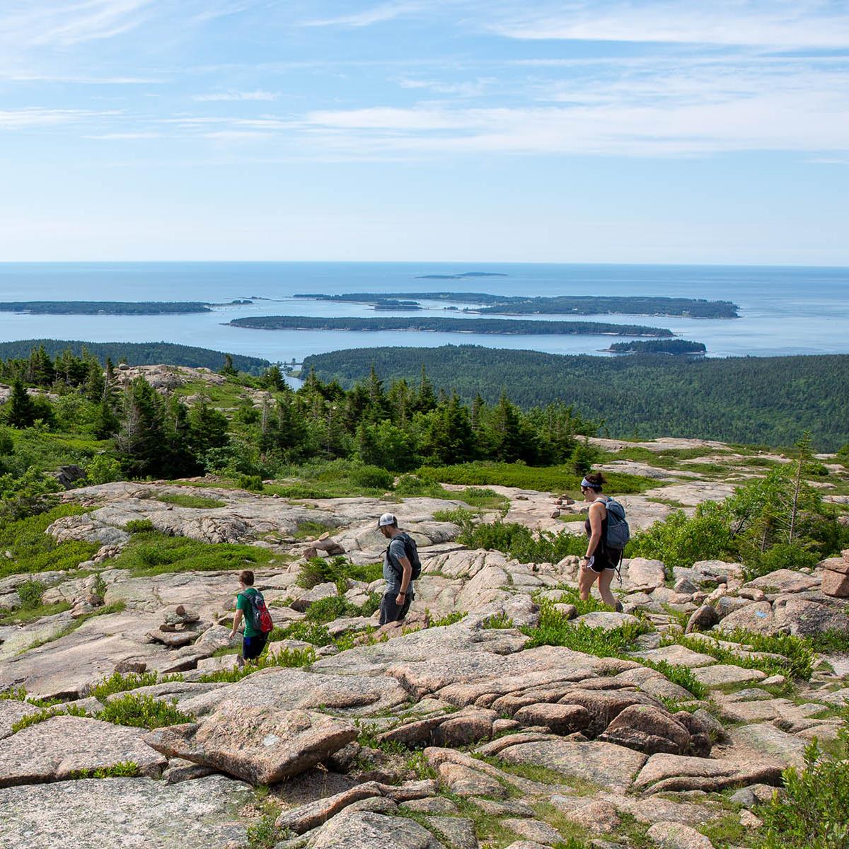 Blue skies above Jordan Pond with views of tree lined North and South Bubble Mountains.  