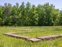 A stone foundation of a house site in a field.