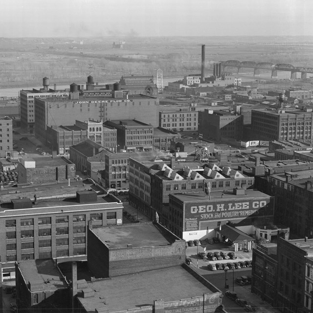 Black and white photo of a historic downtown area and river from a high angle.