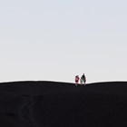 a family at the distant top of a very large, black cinder cone