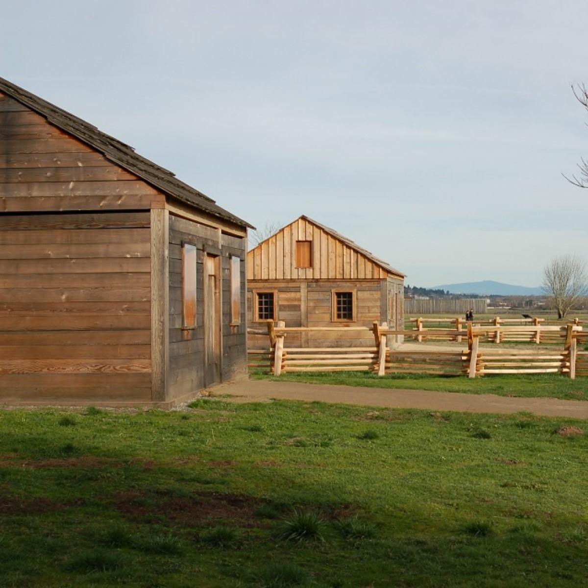 Two small cabins with fences with Mount Hood in the background.