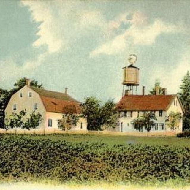 Image of three structures on a farm, including a barn and water tower. 