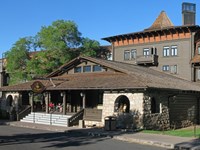 A large, multi-story wooden building features a tall turret and a wide, covered front porch.