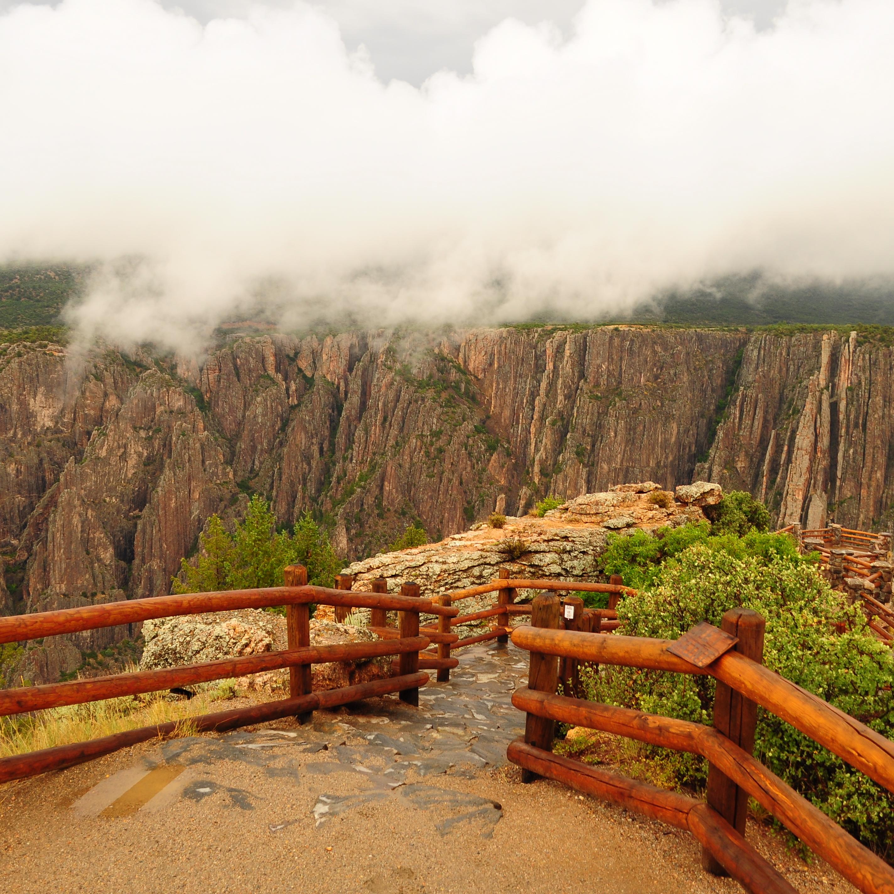 An overlook lined with wooden fencing leading towards a canyon edge
