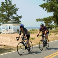 group of bicyclists on a road in Southern Maryland with a glimpse of the Potomac River