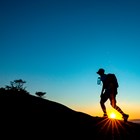 Silhouette of a hiker along a ridge line with sun on the horizon.