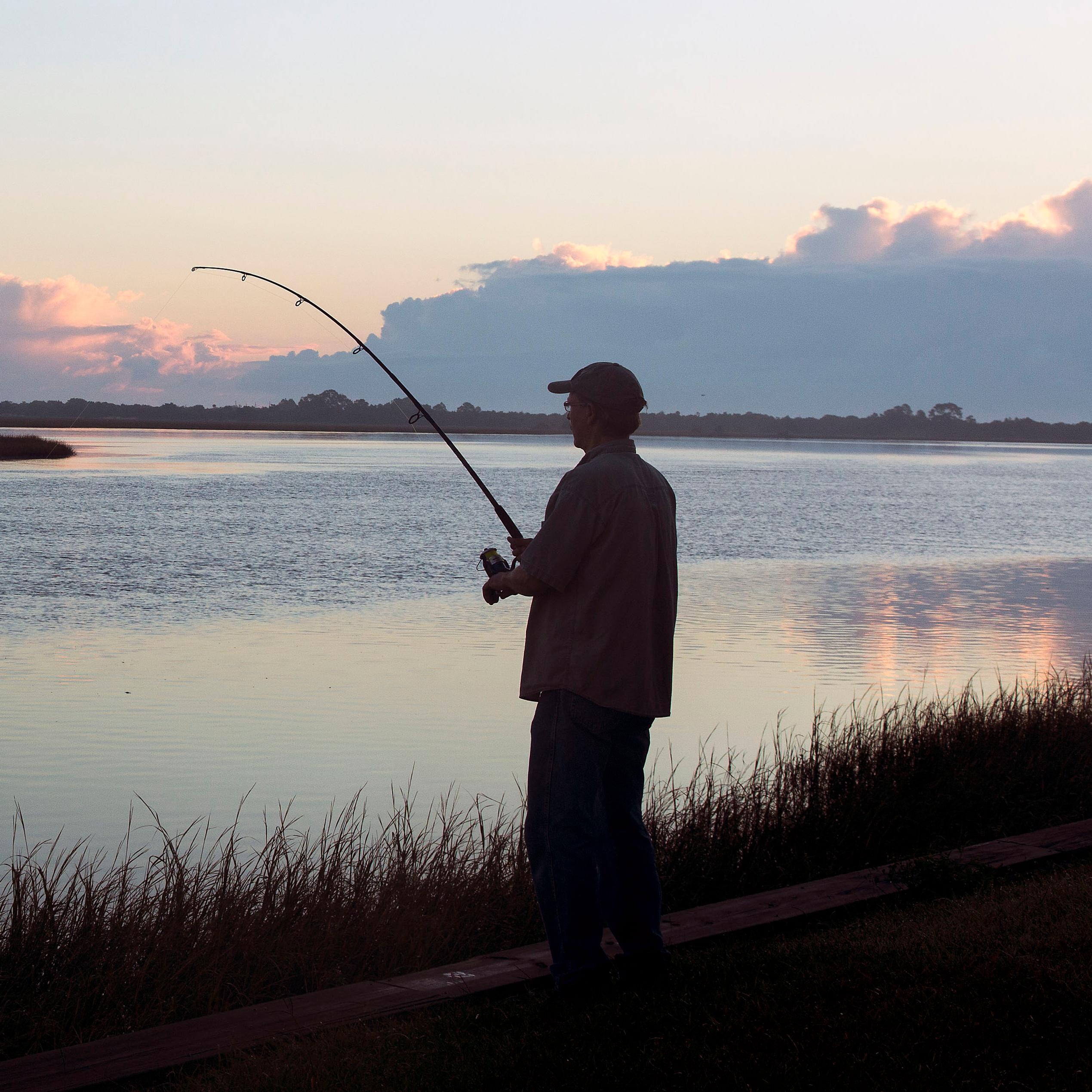 silhouetted angler fishing at dawn