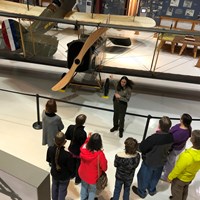 A park ranger talking about a biplane with a group of visitors inside Pearson Air Museum.