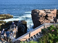 A large rock formation protrudes on the right side, with a set of stairs toward waters edge.