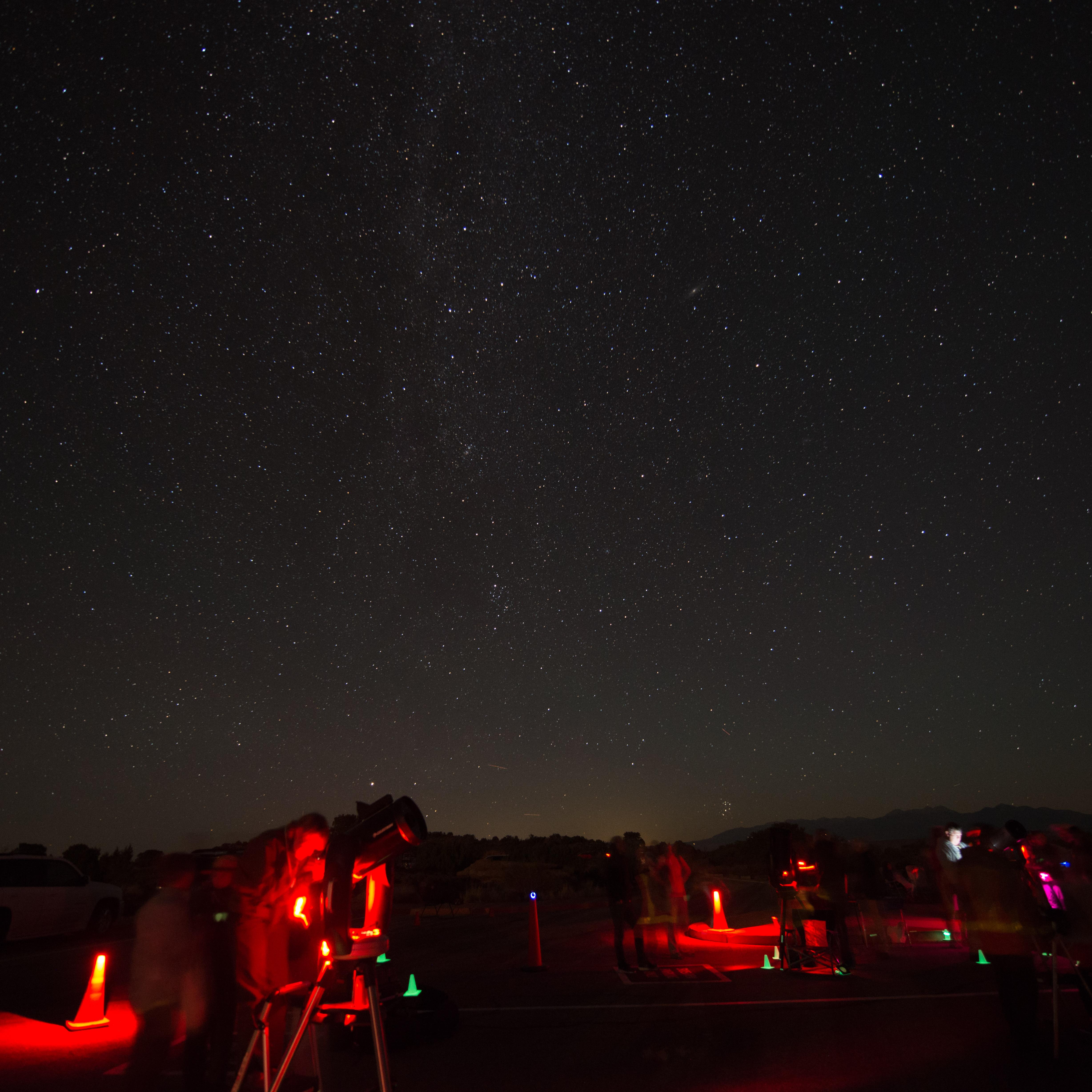 telescopes illuminated red beneath a star-filled sky