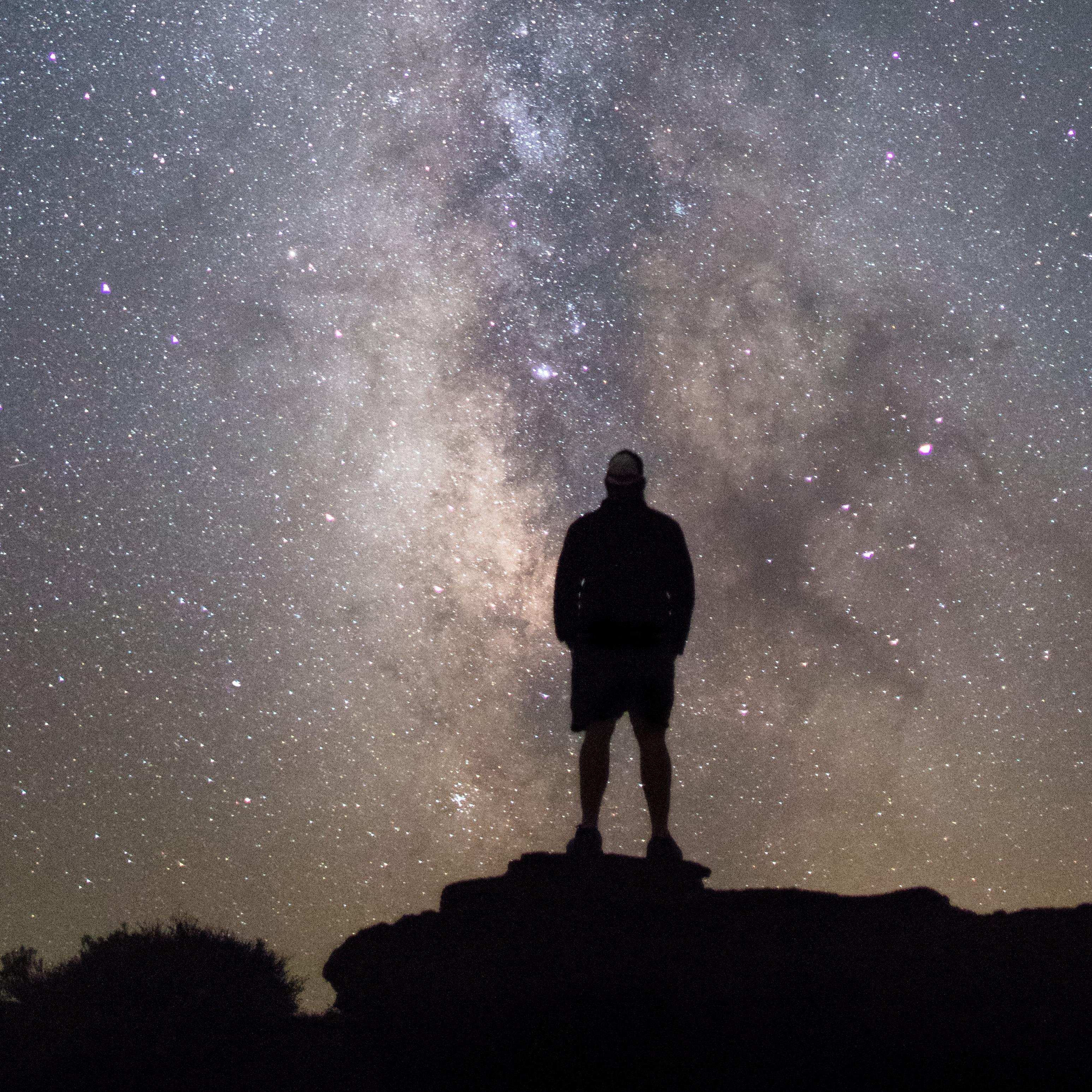 a person standing on a rock silhouetted against the milky way