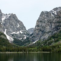 A rocky mountain canyon sits across a calm lake.
