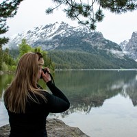 A woman take a picture beside a lake.