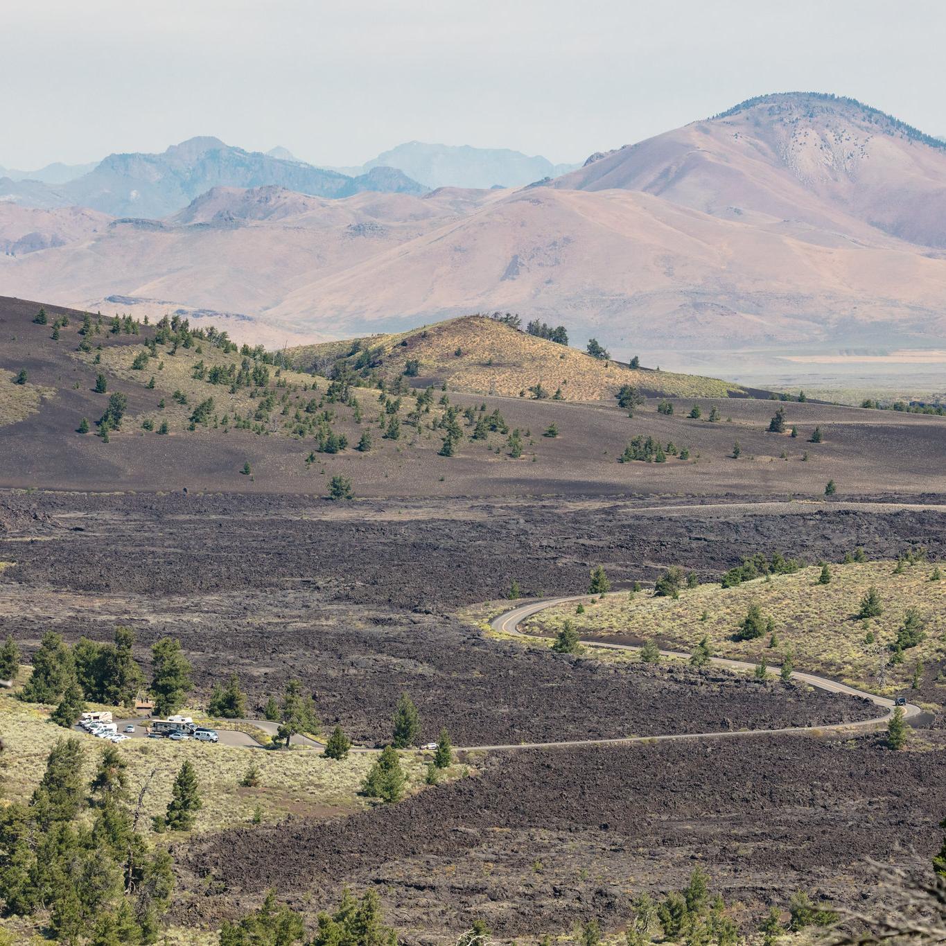 A narrow road winds through a volcanic landscape to a small parking area.