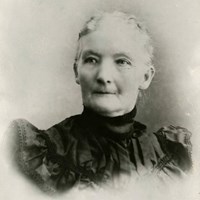 A black and white portrait of a woman with white hair pulled back in a dark colored period dress
