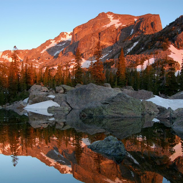 A snow-capped mountain is reflected in a mountain lake