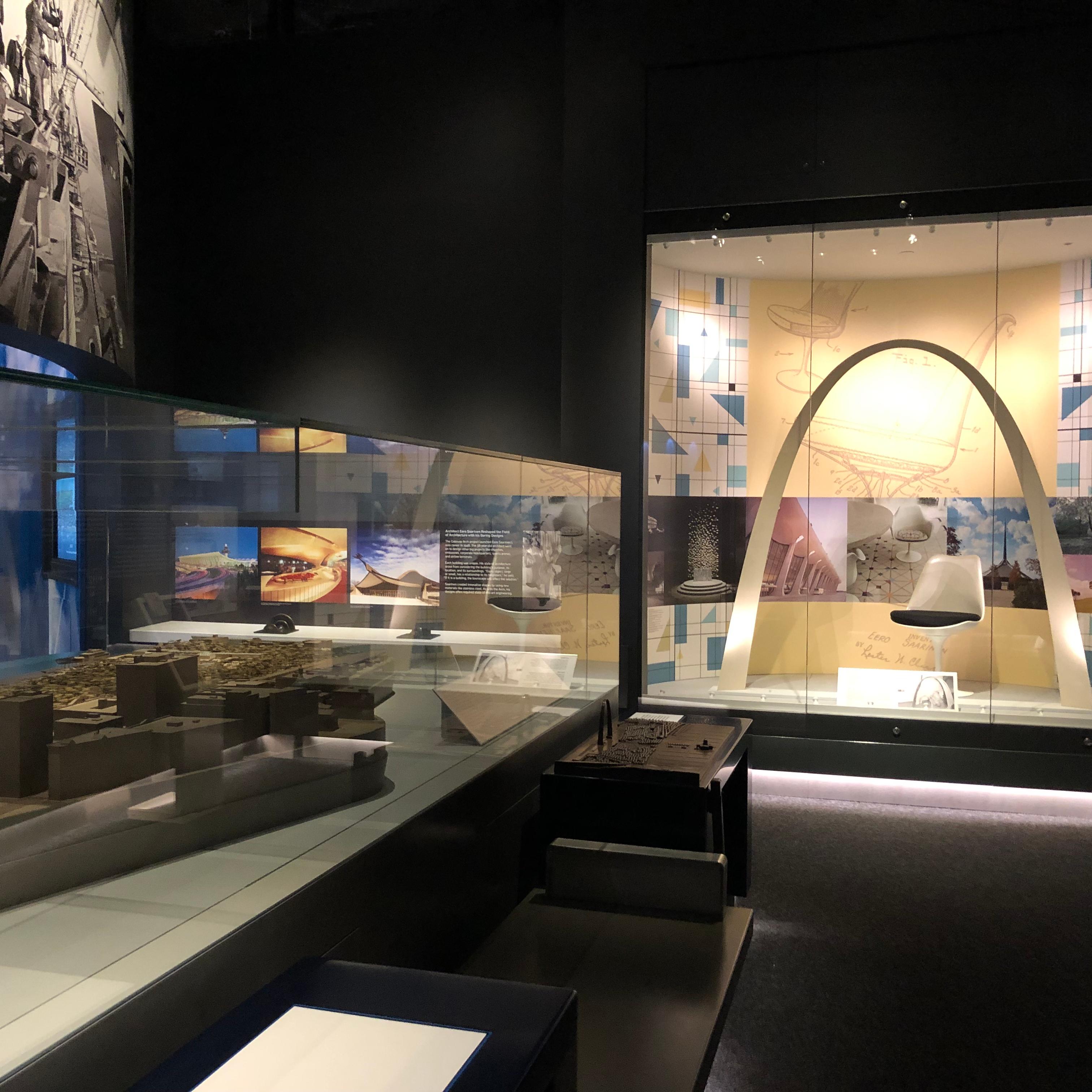 two glass cases, one holding a model of the Arch grounds and one a large model of the Arch structure
