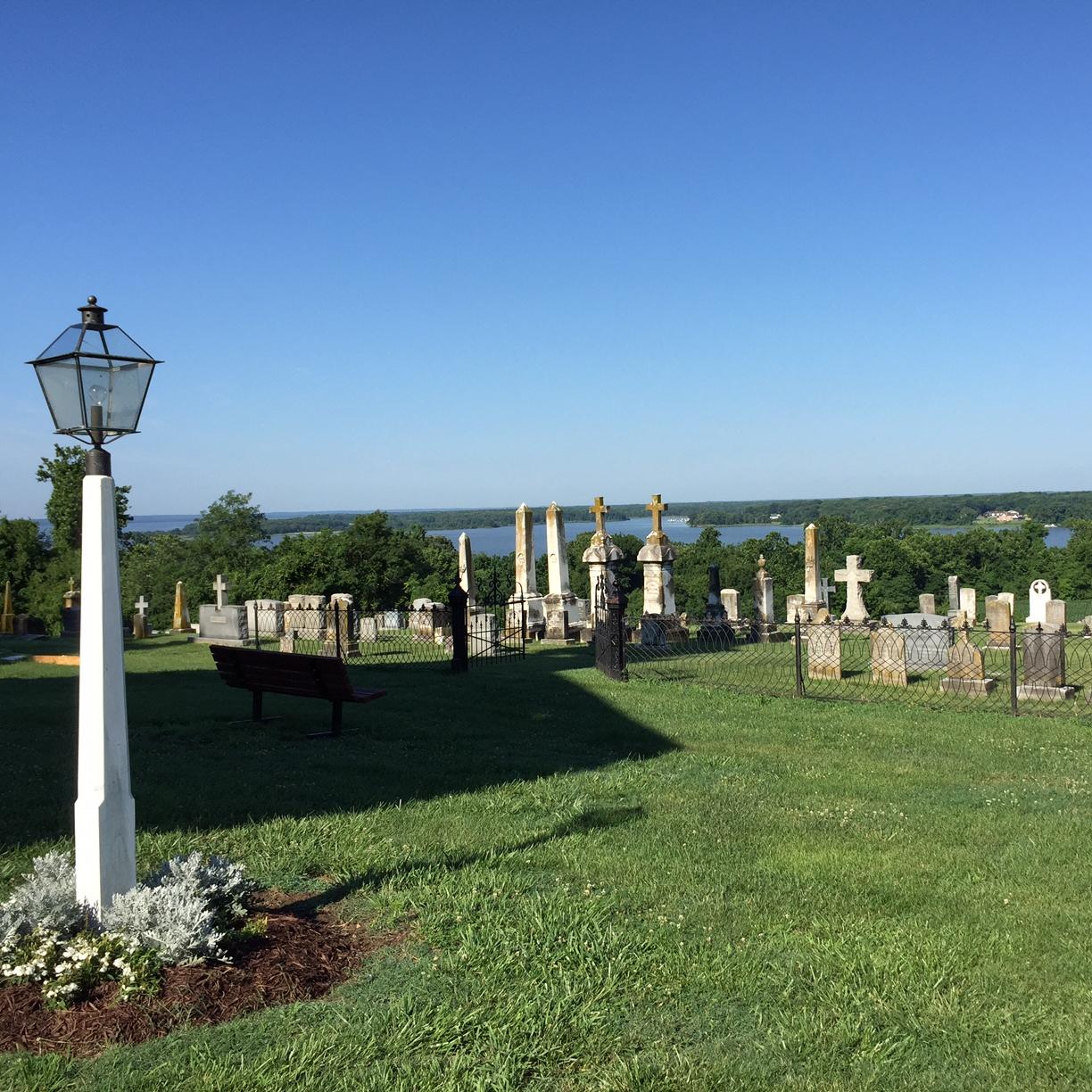 view from a bluff with a cemetery in the foreground and with a creek and forest in the distance 