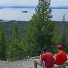 Hikers rest and look out at Yellowstone Lake from atop a mountaintop.