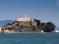 The lighthouse and prison can be seen on Alcatraz island from the water.