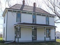 The white two-story Truman home with front porch and green trim.