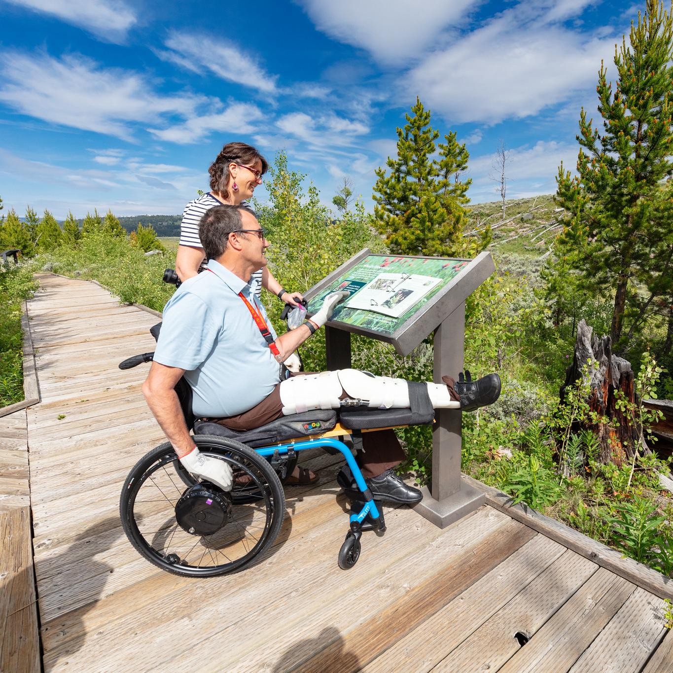 Visitors on a boardwalk view a low profile wayside exhibit