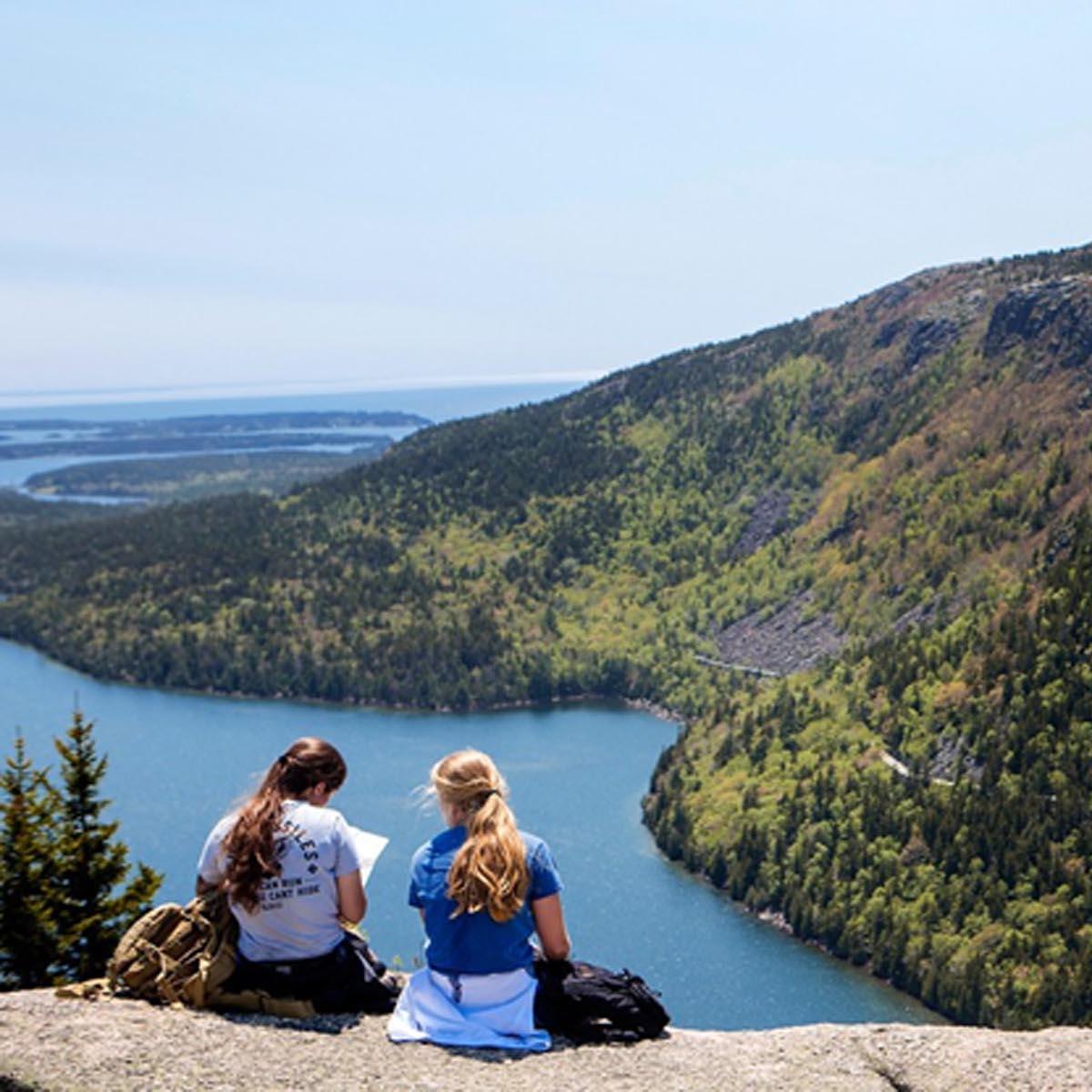 Two hikers sit on the bald granite summit of North Bubble studying a map. 