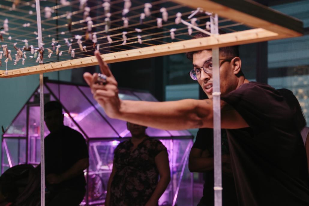 Young man pointing at a chrysilis of a butterfly.