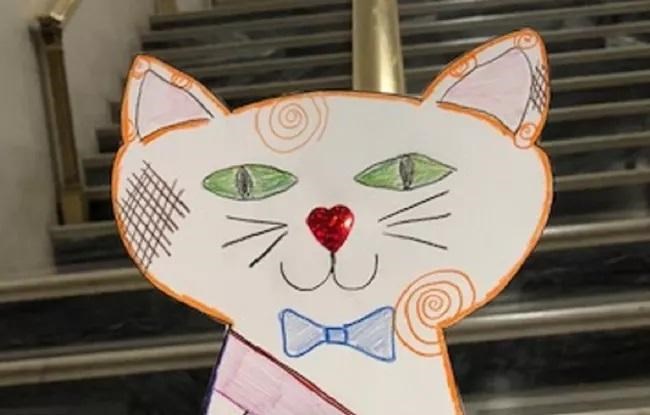 Cut out of child's drawing of cat with green eyes and blue bow tie