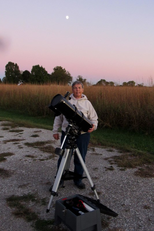 A woman with big telescope outside.