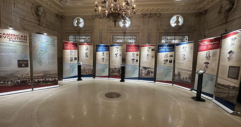 12 pull up banners are arranged in a half circle around a dimly lit room.