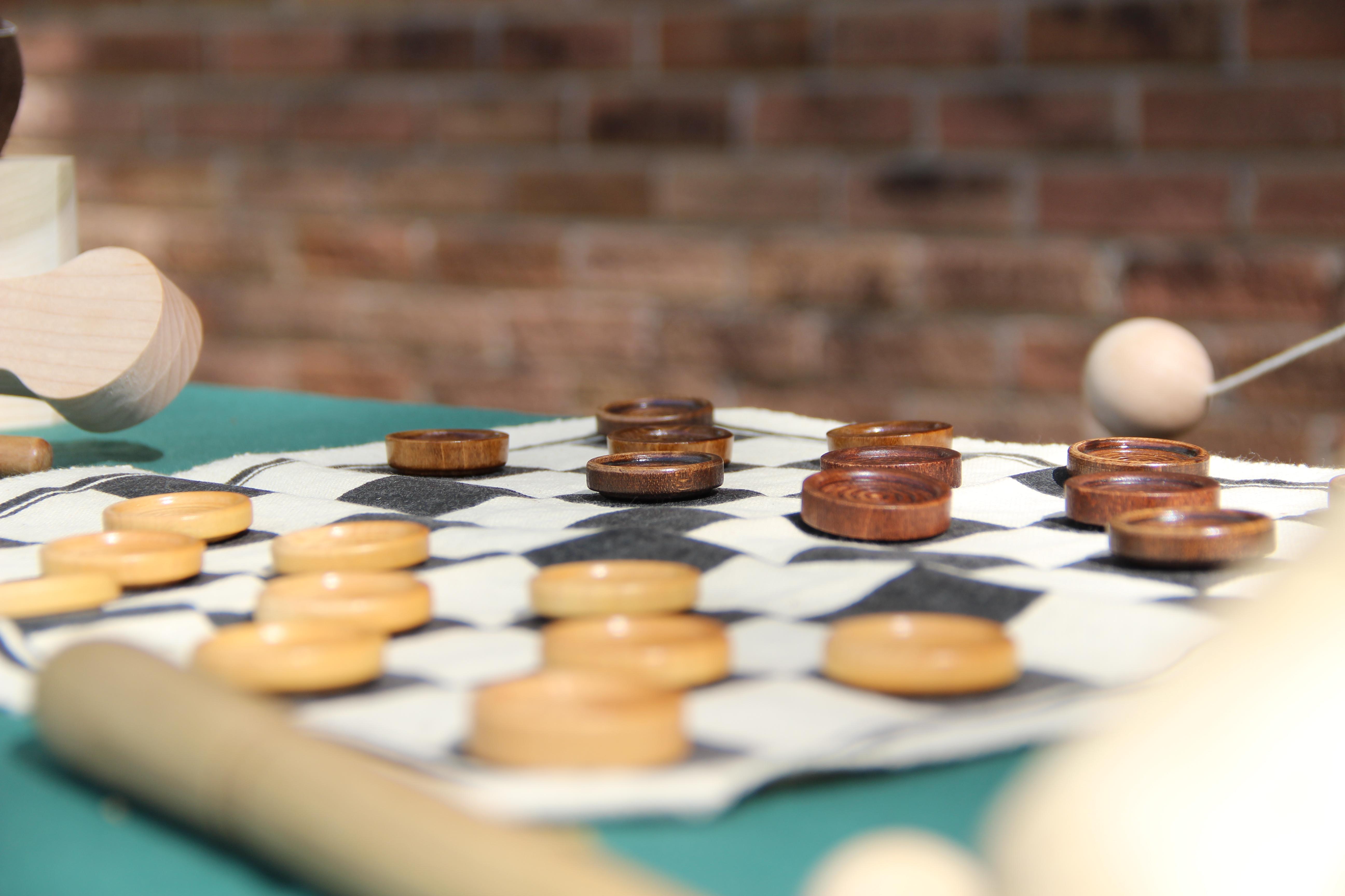 A close-up of a portable checkerboard. The pieces are wood and the board is cloth.