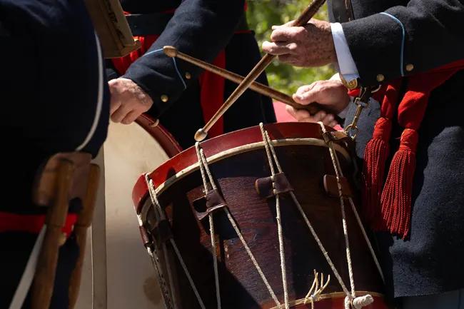 Close up of an 18th-century Revolutionary War era soldier's hands playing a large drum