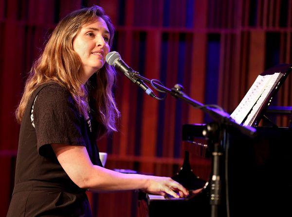 Woman playing a piano and singing in front of a microphone