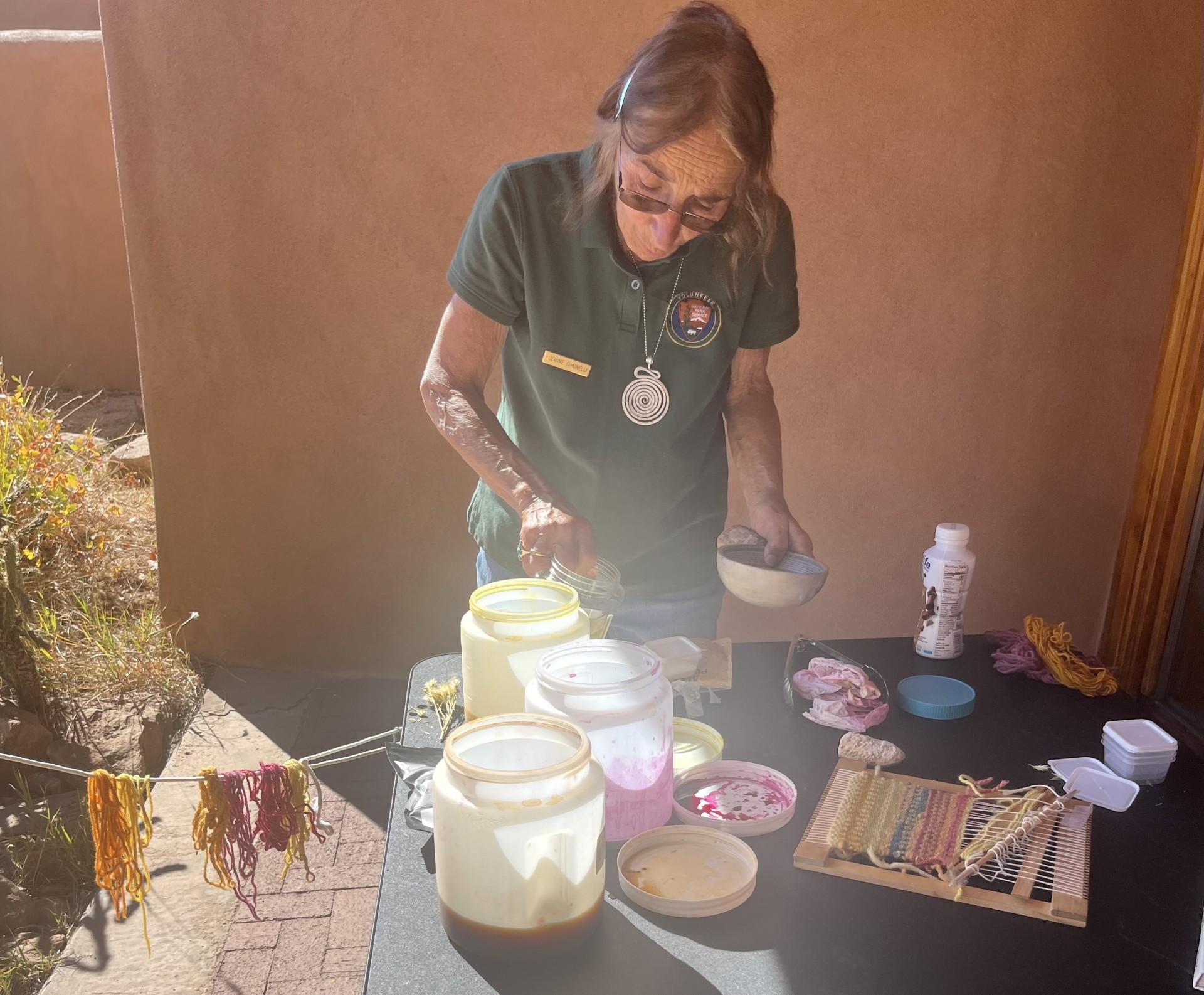 A woman wearing a volunteer shirt dying fiber in natural dyes.