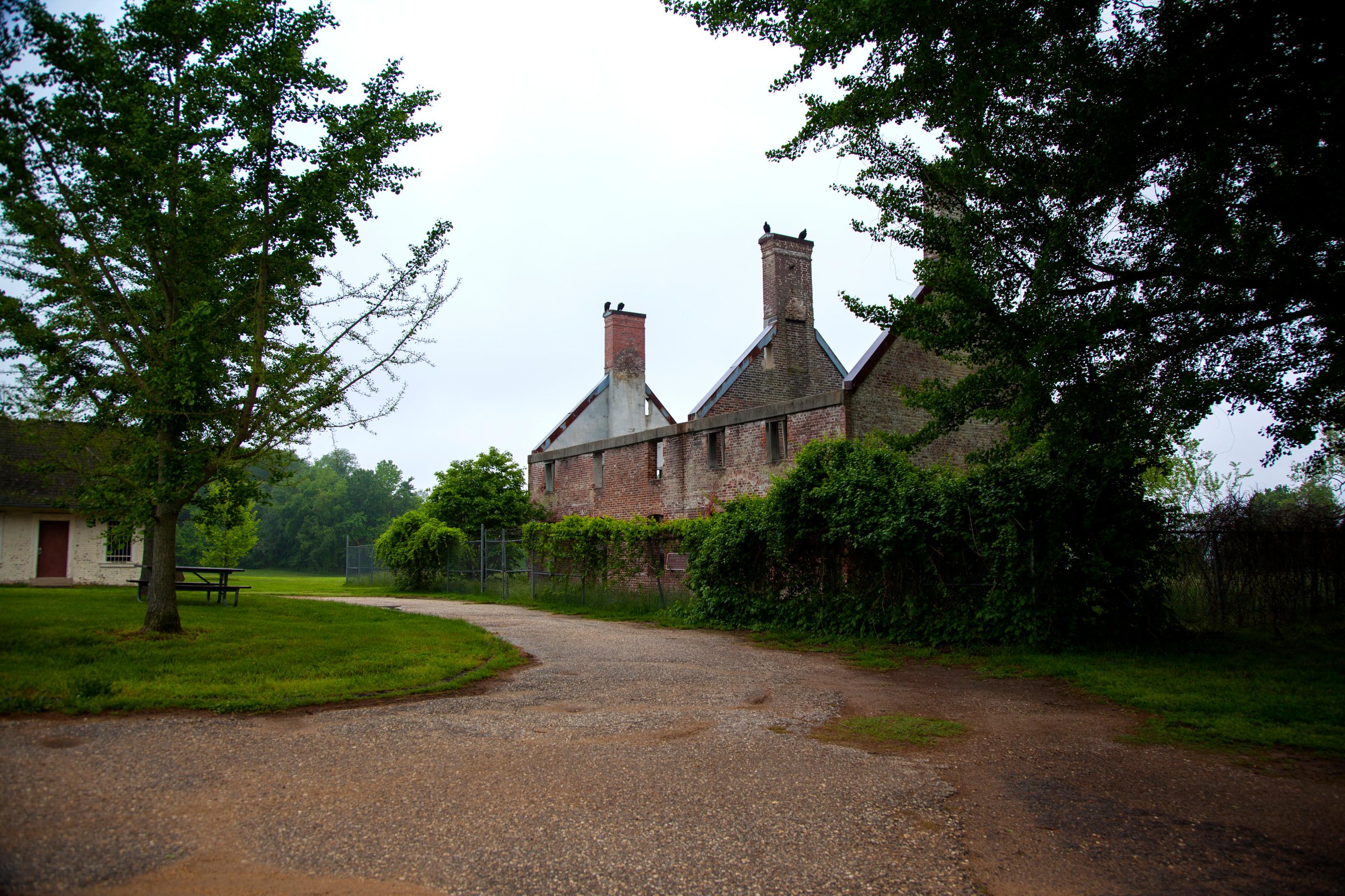 Ruins of a brick building with a wide dirt trail in the foreground.