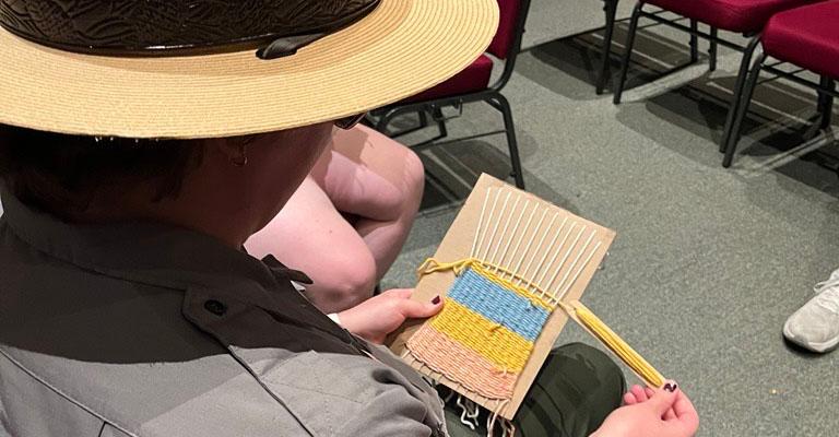 An over-the-shoulder shot of a ranger working on a weaving project.