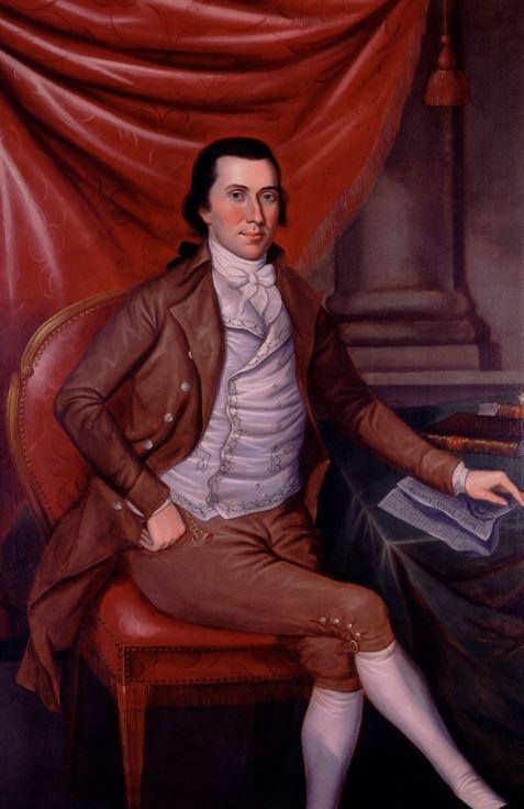 Portrait of a man, seated, with his left arm resting on a table and newspaper. His right arm is bent