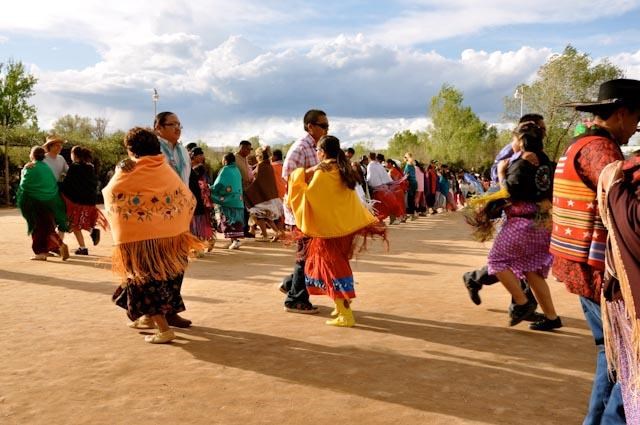 A group of people dancing in a cleared sandy area.