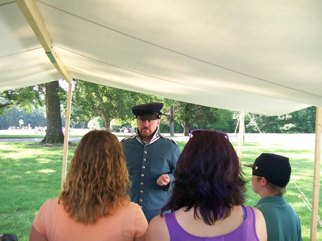 A living historian in Mexican War era uniform talks to visitors under a tent